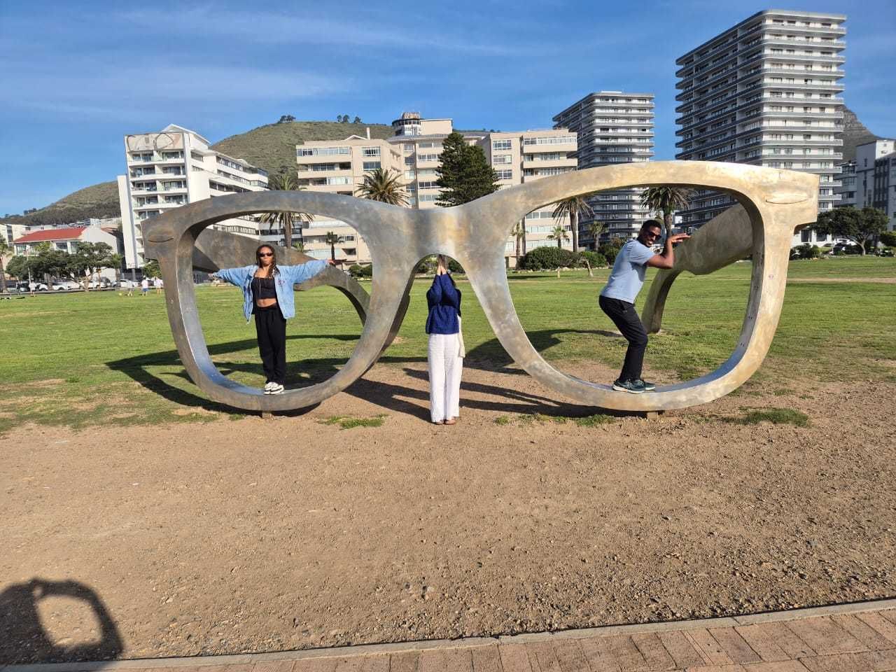 Three timbuk2 team members posing inside the giant steel spectacles sculpture on the Sea Point promenade in Cape Town